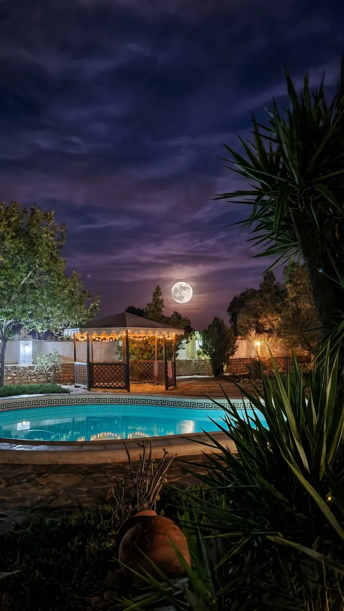 Piscina privada iluminada de noche con cenador y luna llena en Casa Rural de la Cuesta